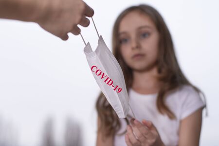 Personal protective equipment required. A little girl is given a protective mask.Covid-19の写真素材
