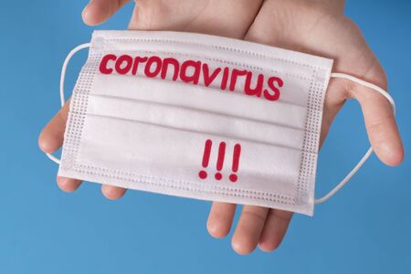 Chinese outbreak of coronavirus. Hands on a blue background with a protective mask with the text Coronavirus.Coronovirus Quarantine Concept.の写真素材