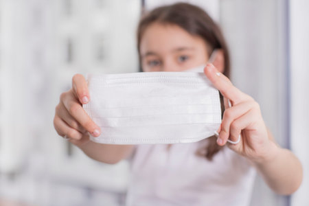 The girl became ill and cannot go out.Coronovirus Quarantine Concept.Little girl offers to wear a...