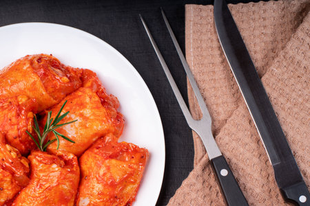 Raw marinated chicken thighs for grill and bbq.Cooking Chicken.Uncooked marinated chicken legs and marinade ingredients on the kitchen board.の写真素材