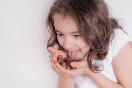 Girl and chocolate.Little girl on a light background with chocolate in her hands.