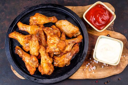 Fried chicken dippers in black bucket with sauce on black background.Chicken breaded strips on a black plate with ketchup and white sauce .の写真素材