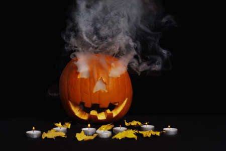 Orange pumpkin for Halloween on a black background with candles. Halloween concept.の写真素材