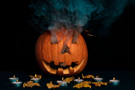 Orange pumpkin for Halloween on a black background with candles. Halloween concept.の写真素材