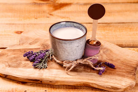 Milk in a cup near chocolate on a kitchen cutting board on a wooden background.の写真素材