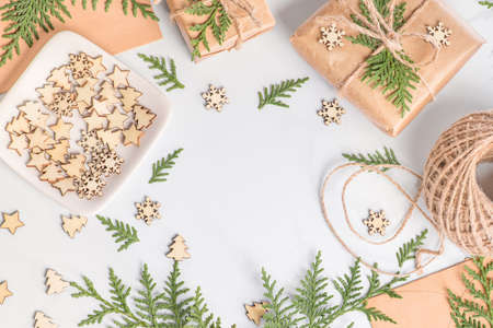 On a white background, gifts are decorated with fresh spruce branches with decorative wooden snowflakes.Christmas or winter composition. Christmas, winter, new year concept.の写真素材