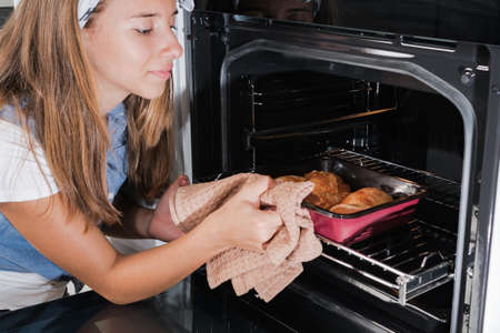 Chicken meat for roasting. The girl puts meat in the baking package in the oven for baking.の写真素材