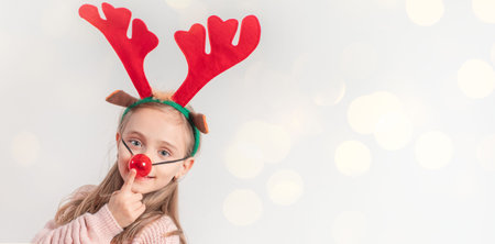 Photo of a funny girl who is wearing Christmas deer antlers on her head on a white background.Copy space.の写真素材