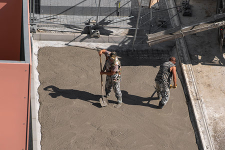 Two men are laying concrete on the sidewalk. Renovation work.