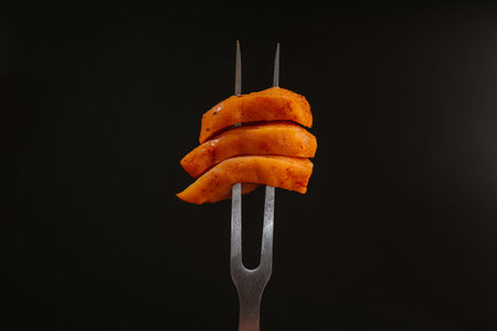 Raw chicken meat. Chicken thinly sliced marinated fillet on a fork on a black background. Diet food....