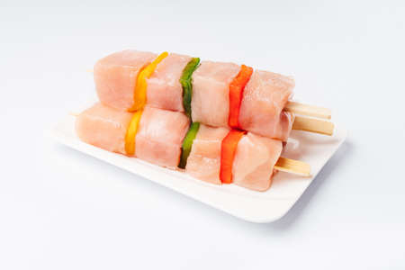 Chicken skewers on skewers on a white plate on a light background.の写真素材