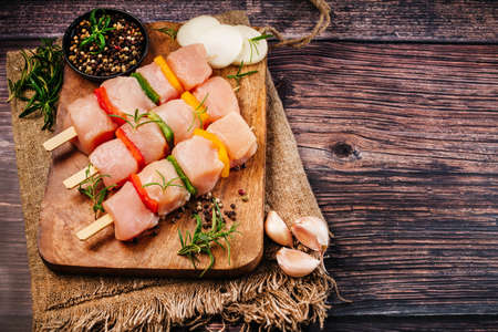 Chicken skewers on skewers on a wooden kitchen board with spices on a wooden background.の写真素材
