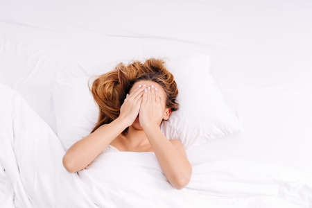 Heavy morning.Woman suffering lack of sleep.A young girl is too lazy to get out of bed, sleep, early morning.Heavy morning awakening after hangover.の写真素材