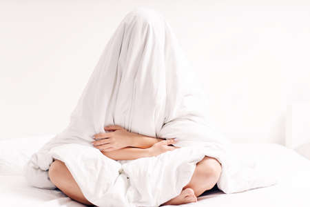 Heavy morning.Woman suffering lack of sleep.A young girl is too lazy to get out of bed, sleep, early morning.Heavy morning awakening after hangover.の写真素材