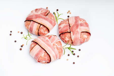 Raw chicken burger on a white plate in a rosemary branch and spices. Instant meat. Grilled hamburgers.Raw Hamburger, meatballs on white background.Fast food at home.Convenience food, precooked.の写真素材