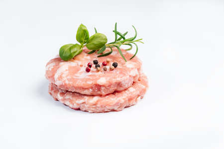 Raw chicken burger on a white plate in a rosemary branch and spices. Instant meat. Grilled hamburgers.Raw Hamburger, meatballs on white background.Fast food at home.Convenience food, precooked.の写真素材