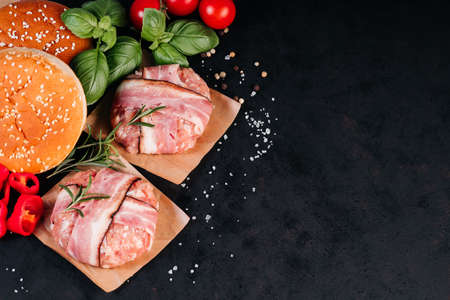 Grilled hamburgers.Copy space.Raw chicken burger on a wooden kitchen board with a rosemary branch, tomatoes, garlic, paprika and spices. Instant meat.の写真素材