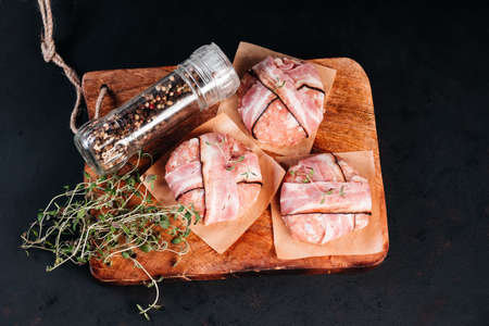 Grilled hamburgers.Copy space.Raw chicken burger on a wooden kitchen board with a rosemary branch and spices. Instant meat.の写真素材