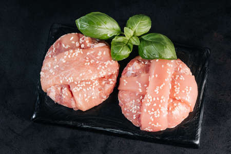 Grilled hamburgers.Raw chicken burger with basil leaves and spices on a black background. Instant meat.の写真素材