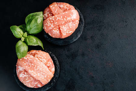 Grilled hamburgers.Copy space.Raw chicken burger with basil leaves and spices on a black background. Instant meat.の写真素材