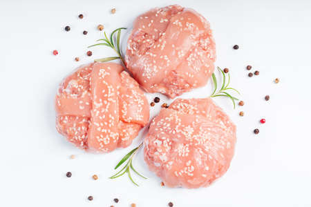 Raw chicken burger on a white plate in a rosemary branch and spices. Instant meat. Grilled hamburgers.Raw Hamburger, meatballs on white background.Fast food at home.Convenience food, precooked.の写真素材