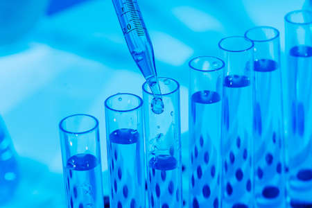 Laboratory glassware with a dropper dripping liquid into a test tube. scientific laboratory test tubes, laboratory equipment.Coronavirus pandemic stop. Medicine concept. Development of new vaccines.の写真素材