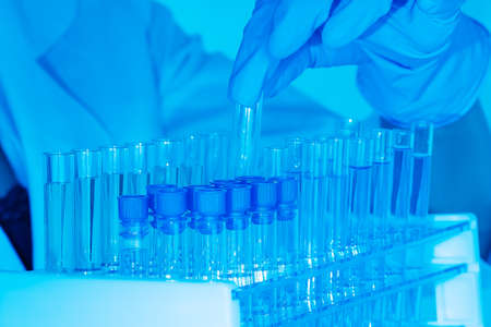 Chemical laboratory. Control of the composition of drugs. Development of new vaccines.hand of scientist holding flask with lab glassware and test tubes in chemical laboratory background, science laboratory research and development concept.の写真素材