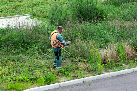 Process of lawn trimming with hand mower.lawn mower worker cutting grass in green field.Worker...