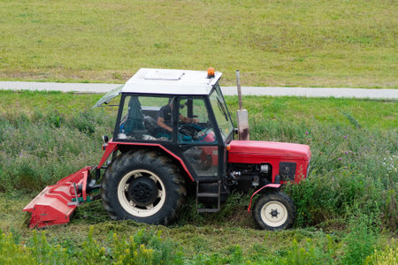 Tractor with trailer Mowing grass.Ride-on lawnmower.tractor mows lawn grass in the city.