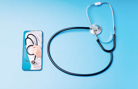 video call.The concept of a doctor on a phone call. Doctor online. Doctor call, offline. Phone on a blue background with a stethoscope, the phone displays a doctor with a stethoscope.の写真素材