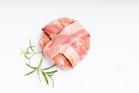 Hamburger with bacon on a white plate with a branch of rosemary. Raw chicken hamburger.
