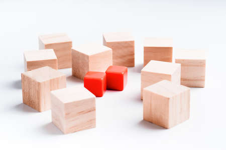 Wooden and red plastic cubes on a white background. Many wooden cubes but only two red ones. Concept for choosing priorities. Business, choice, decision.Not like everyone else.の写真素材