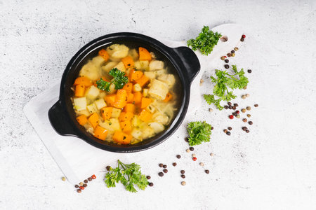 Chicken soup with pasta and herbs on a wooden kitchen board on background.