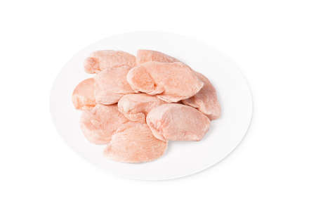 Frozen pieces of fresh chicken meat on a white plate. Isolade.Raw frozen fillet isolated on white background.の写真素材