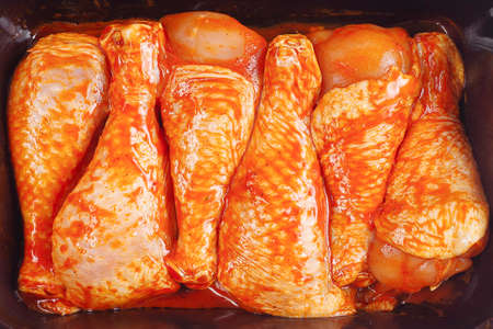 Raw chicken drumstick with spices and green rosemary on a black background.の写真素材