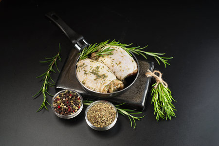 Chicken thighs with spices, garlic.Close-up, top view.Raw chicken thighs marinated in herbal sauce on a dark background with fresh rosemary, spices.Copy space.Raw Meat Chicken.の写真素材