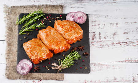 Three pieces of chicken thighs marinated in red sauce on a kitchen cutting board, on a light background, banner. Top view.Convenience food, quick cook, semi-cooked food.Free space, copy space.の写真素材