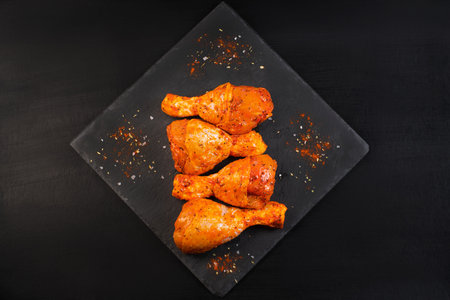 Top view.Hot grilled chicken leg sprinkled with rosemary on a black background. Raw chicken legs....