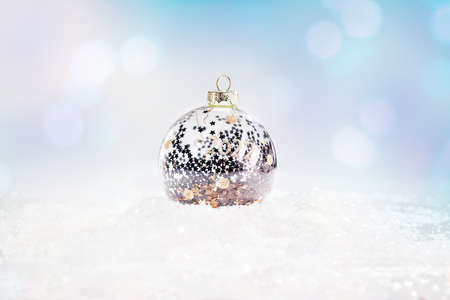 Shiny, silver glass Christmas ball on snow on a light background. Glittering,Shiny background.Christmas, winter, new year concept.copy space.Winter Background.Xmas and New Year holiday, bokeh, lightの写真素材