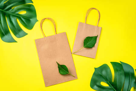 Eco-friendly paper bags on yellow background.Recycled paper shopping bag with green leaves .Set of multiple disposable paper bags for takeaway food, gifts,and mock up.の写真素材