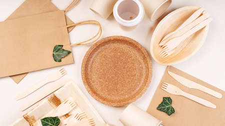 Eco craft paper tableware,cups,fast food containers.Recycling,eco-friendly concept.Disposable eco cutlery,plates,spoons,knives,forks on a light background.Craft paper bag for food delivery.Copy space.の写真素材