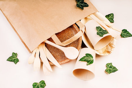 Craft paper bag for food delivery.Copy space.Eco craft paper tableware,cups,fast food containers.Recycling,eco-friendly concept.Disposable eco cutlery,plates,spoons,knives,forks on a light background.の写真素材