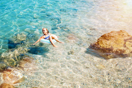 Beach holidays on vacation.Children on inflatable rings in the warm sea.The child is having fun on the waves,on the seaside.Summer holidays at the seaside.Children have fun on a summer sunny day.の写真素材