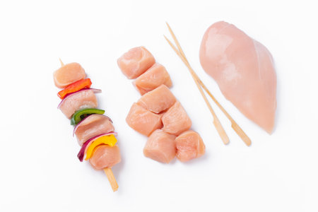 Raw chicken skewers with vegetables, peppers,onions,white background.Chicken Skewers breast fillet meat.Uncooked meat skewer with peppers.Skewers with pieces of raw meat,red,yellow pepper.Top view.の写真素材