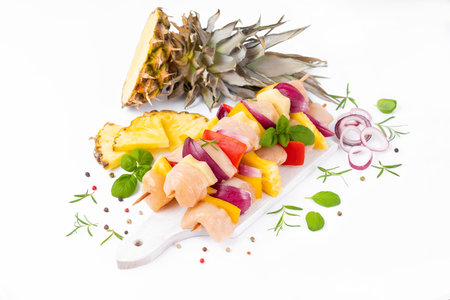 Uncooked meat skewer.Raw pieces of chicken skewers with pepper onion and pineapple white background.Skewers with pieces of raw meat, red, yellow pepper.Top view.Chicken Skewers breast fillet meat.の写真素材