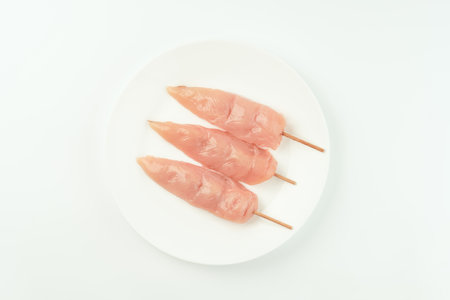 Chicken skewers.Food concept.Skewers from raw chicken meat inner fillet on a white plate for a supermarket on a white background..Ogranic food,healthy eating.Food for retail.Top view.の写真素材