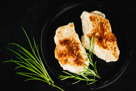 Chicken fillets fried until half cooked,product.Quick cooking at home.Semi-finished chicken fillets,lightly fried,on a dark background with fresh herbs.Half-finished.Quick cooking at home.Fast food.の写真素材