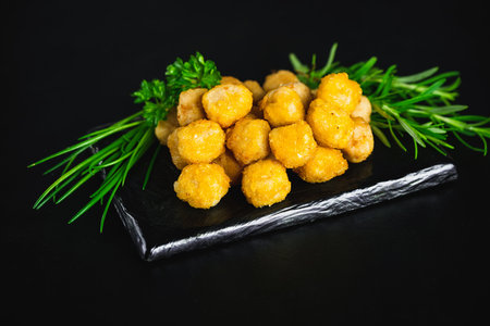 Breaded chicken nuggets. Semifinished chicken nuggets from chicken fillet on a dark background with fresh herbs. Quick cooking at home. Fast food. Breaded Chicken Inner Fillet.の写真素材