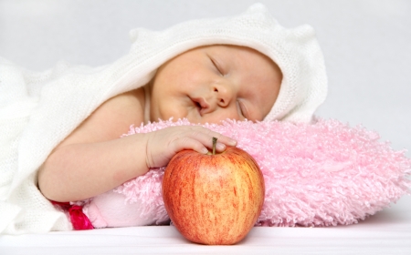 Sleeping baby with an apple in handの写真素材