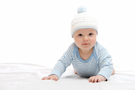 Beautiful baby in  blue hat on the bed